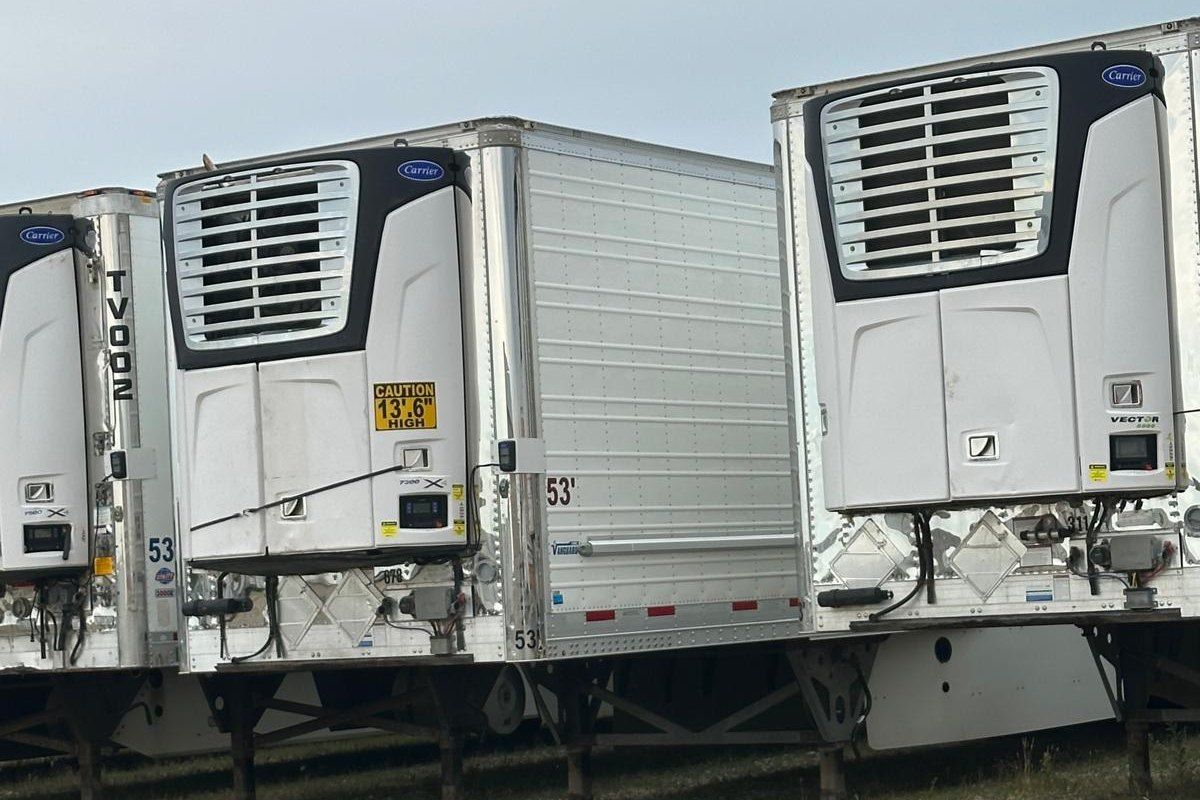 A row of white reefer trailers parked in a yard